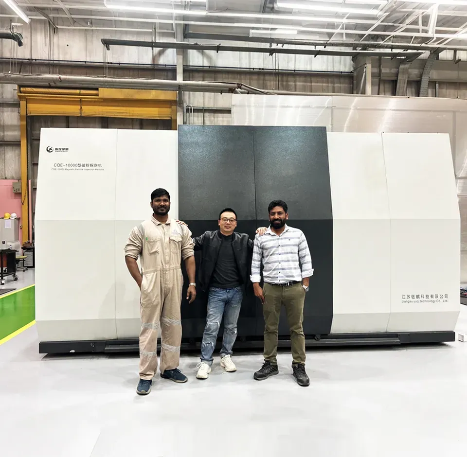 Three people in front of a finished CQE-10000 crankshaft magnetic particle inspection machine