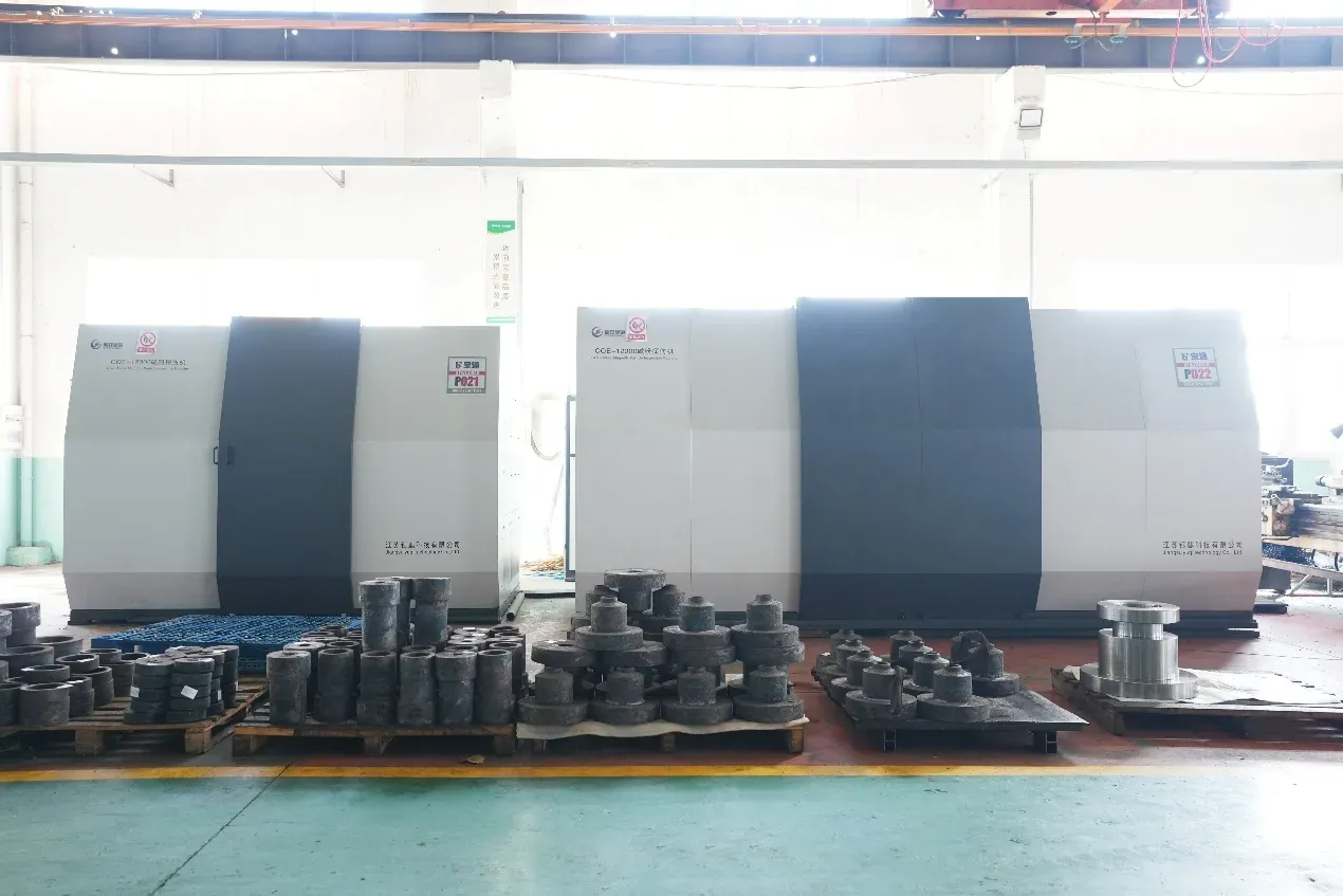 Two CQE machines side by side in a workshop, with forgings on pallets in front