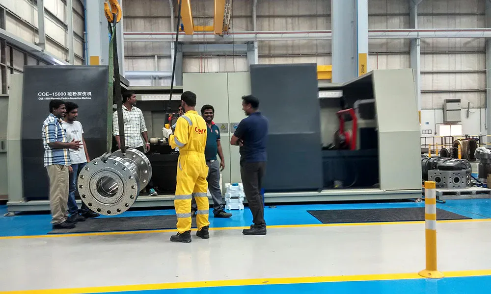 Customer staff and an engineer beside a CQE-15000 machine while a forged part is lifted in