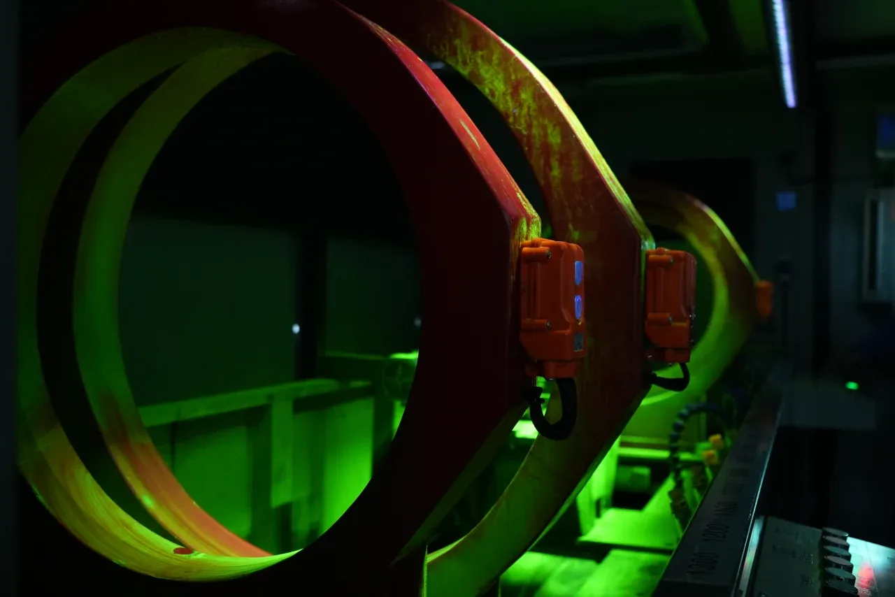 Magnetizing coils of a CQE-8000 axle magnetic particle inspection machine glowing under UV-A light