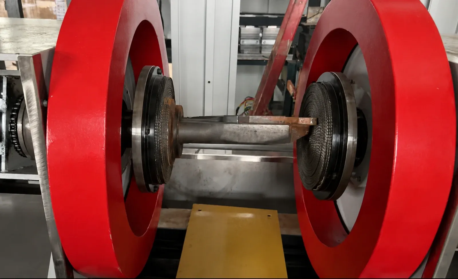 Forged blank clamped between two braided contact pads inside red magnetizing coils