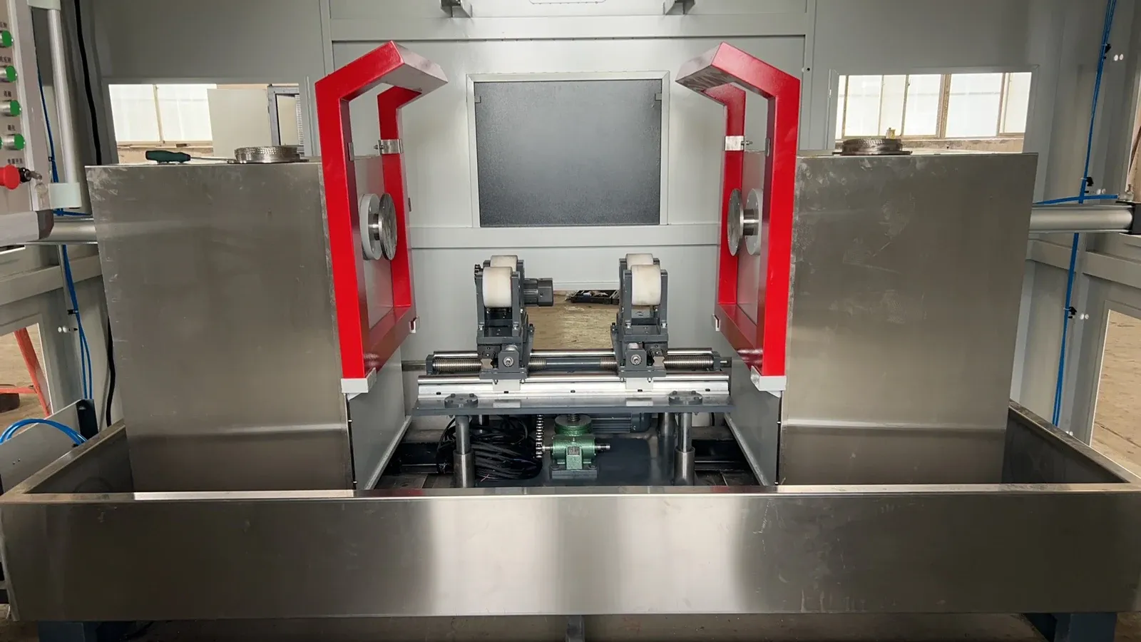 Inspection area with support rollers between two red magnetizing frames above a stainless steel tank