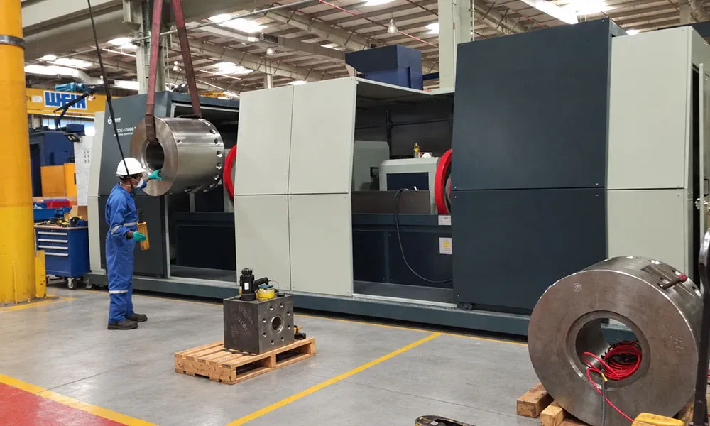 Operator guiding a large ring part on a crane into a CQE-15000 machine