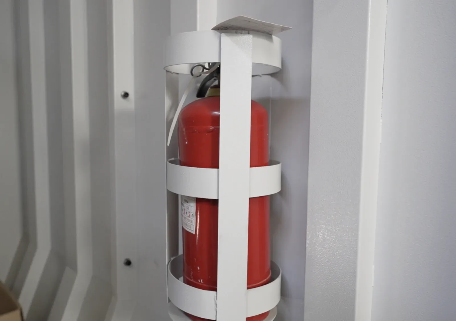 Fire extinguisher in a bracket built into an inspection machine enclosure