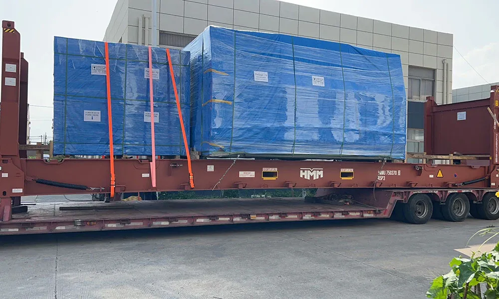 Two magnetic particle inspection machines wrapped in blue film and strapped onto a flat-rack container for export